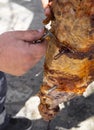 A man is chopping meat with an axe-knife traditional food - goat or lamb on a spit - for the Easter holiday on a wooden block on t