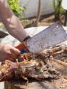 A man is chopping meat with an axe-knife traditional food - goat or lamb on a spit - for the Easter holiday on a wooden block on t