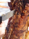 A man is chopping meat with an axe-knife traditional food - goat or lamb on a spit - for the Easter holiday on a wooden block on t