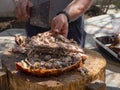 A man is chopping meat with an axe-knife traditional food - goat or lamb on a spit - for the Easter holiday on a wooden block on t