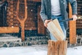 Man chopping wood on snowy yard for a house fireplace with heavy snowflakes background . Winter countryside holidays concept image Royalty Free Stock Photo