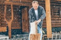 Man chopping wood on snowy yard for a house fireplace with heavy snowflakes background . Winter countryside holidays concept image Royalty Free Stock Photo