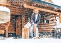 Man chopping wood on snowy yard for a house fireplace with heavy snowflakes background . Winter countryside holidays concept image