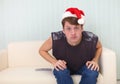Man in Christmas cap sits on sofa and watches TV Royalty Free Stock Photo