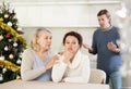 Man on christmas eve quarrels with his wife in kitchen, standing behind her, and elderly mother hugs and calms her Royalty Free Stock Photo