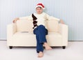 Man in Christmas hat sits on sofa and watches TV Royalty Free Stock Photo