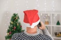 A man in a christmas hat is talking the phone Christmas Eve or New Year& x27;s Eve. A young man in christmas hat makes