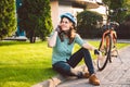 Man and city rolling bicycle, environmentally friendly transport. Beautiful young caucasian woman worker sitting resting on the gr