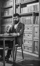 Man in classic suit sits in vintage interior, library, book shelves on background. Aristocratic lifestyle concept