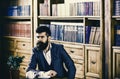 Man in classic suit sits in vintage interior, library, book shelves on background. Oldfashioned man near cup with tea Royalty Free Stock Photo