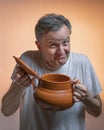 A man with a clay pot in one hand and the lid in the other hand makes a funny face Royalty Free Stock Photo