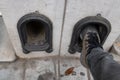 Man clean his shoes on boot scraper in a low wall at the entrance to the drive of a terraced house. Metal arch shaped with face