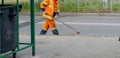 Man cleaner sweeping street with broom, municipal worker in uniform with broomstick brush for garbage in hands, cleaning