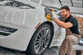 Man cleaning car and drying vehicle with microfiber cloth. Hand wipe down paint surface of shiny white car after polishing and Royalty Free Stock Photo