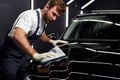 Male cleaning and drying vehicle with microfiber cloth. male wipe down paint surface of shiny black car after polishing Royalty Free Stock Photo
