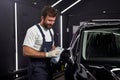 Man cleaning and drying vehicle with microfiber cloth. male wipe down paint surface of shiny black car after polishing Royalty Free Stock Photo