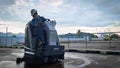 A man is cleaning a cement floor using a floor cleaning machine in a cemented area in a factory Royalty Free Stock Photo