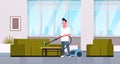 Man cleaning couch with vacuum cleaner guy doing housework concept modern living room interior male cartoon character Royalty Free Stock Photo