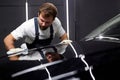 Man cleaning and drying vehicle with microfiber cloth. male wipe down paint surface of shiny black car after polishing Royalty Free Stock Photo