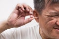 Man cleaning ear with cotton buds stick with ticklish expression