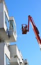 Man cleaning facade of a modern minimalistic apartment building on a telescopic boom lift using pressure jet wash with blue sky Royalty Free Stock Photo