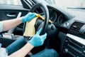 Man cleaning his car interiors and dashboard wheel from dust