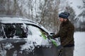 Man cleaning his car from snow with a brush in a winter day Royalty Free Stock Photo