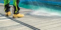 Man Cleaning His Poolside Deck with a Water
