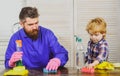 Man cleaning house together at home. Father and son with clean supplies on. Parents and child with rubber glove in foam