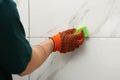 Man cleaning joint between ceramic tiles with sponge on wal. Building and renovation works