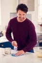 Man Cleaning Kitchen Counter With Spray And Cloth After Cake Baking Royalty Free Stock Photo