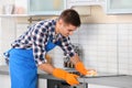 Man cleaning kitchen stove with sponge Royalty Free Stock Photo