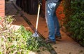 Man cleaning leaves and branches with garden lawn rake after cutting Royalty Free Stock Photo