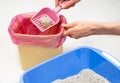 Man cleaning non-Natural mineral Cat Litter tray at home and throws out non-biodegradable Bentonite solid clumps in plastic