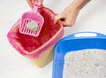 Man cleaning non-Natural mineral Cat Litter tray at home and throws out non-biodegradable Bentonite solid clumps in plastic