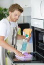 Man cleaning oven in kitchen Royalty Free Stock Photo