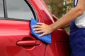 Man cleaning red auto with duster, closeup. Royalty Free Stock Photo