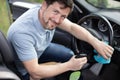 man cleaning salon with rag in car