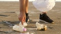 Man cleaning sandy beach from plastic on seashore. Volunteer collect garbage in a trash bag. Ocean plastic pollution Royalty Free Stock Photo