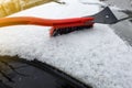 Man cleaning snow from car with brush