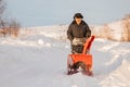 Man cleaning snow from sidewalks with snowblower machine winter