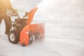 Man cleaning snow from sidewalks with snowblower machine winter