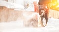 Man cleaning snow from sidewalks with snowblower machine winter