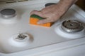 Man is cleaning the stove with kitchen sponge