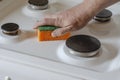 Man is cleaning the stove with kitchen sponge
