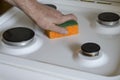 Man is cleaning the stove with kitchen sponge