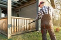 Man cleaning terrace with a power washer - high water pressure cleaner on wooden terrace railing