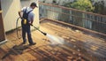 man cleaning terrace with a power washer - high water pressure cleaner on wooden terrace surface Royalty Free Stock Photo