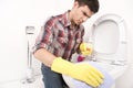 Man cleaning toilet with spray cleaner.