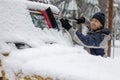 A man is cleaning the windshield of a car with a snow brush Royalty Free Stock Photo